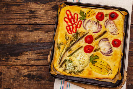 Colorful Garden Focaccia. Fresh ripe vegetables, olive oil, greens. Traditional Italian bakery. Old wooden boards backgroundの写真素材