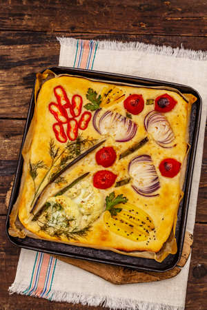 Colorful Garden Focaccia. Fresh ripe vegetables, olive oil, greens. Traditional Italian bakery. Old wooden boards backgroundの写真素材