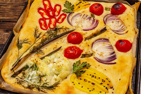 Colorful Garden Focaccia. Fresh ripe vegetables, olive oil, greens. Traditional Italian bakery. Old wooden boards backgroundの写真素材