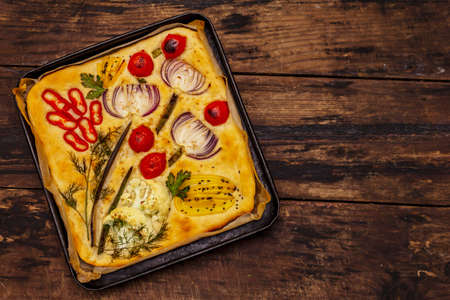 Colorful Garden Focaccia. Fresh ripe vegetables, olive oil, greens. Traditional Italian bakery. Old wooden boards backgroundの写真素材