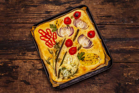 Colorful Garden Focaccia. Fresh ripe vegetables, olive oil, greens. Traditional Italian bakery. Old wooden boards backgroundの写真素材