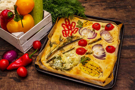 Colorful Garden Focaccia. Fresh ripe vegetables, olive oil, greens. Traditional Italian bakery. Old wooden boards backgroundの写真素材