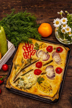 Colorful Garden Focaccia. Fresh ripe vegetables, olive oil, greens. Traditional Italian bakery. Old wooden boards backgroundの写真素材