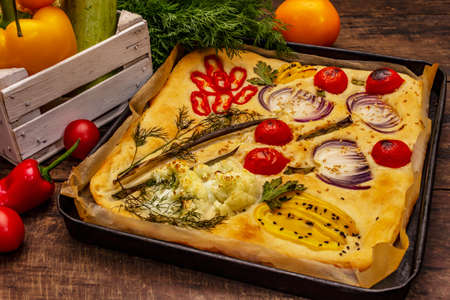 Colorful Garden Focaccia. Fresh ripe vegetables, olive oil, greens. Traditional Italian bakery. Old wooden boards backgroundの写真素材