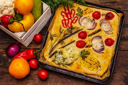 Colorful Garden Focaccia. Fresh ripe vegetables, olive oil, greens. Traditional Italian bakery. Old wooden boards backgroundの写真素材
