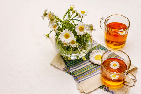 Chamomile tea. Fresh flowers, summer hot drink concept. Alternative medicine, lifestyle. White putty background, copy spaceの写真素材