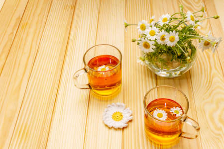 Chamomile tea. Fresh flowers, summer hot drink concept. Alternative medicine, lifestyle.Wooden boards background, copy spaceの写真素材