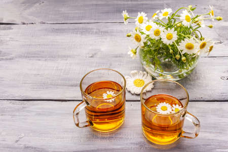 Chamomile tea. Fresh flowers, summer hot drink concept. Alternative medicine, lifestyle.Wooden boards background, copy spaceの写真素材