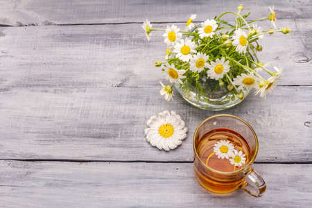 Chamomile tea. Fresh flowers, summer hot drink concept. Alternative medicine, lifestyle.Wooden boards background, top viewの写真素材
