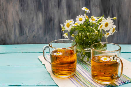 Chamomile tea. Fresh flowers, summer hot drink concept. Alternative medicine, lifestyle. Trendy turquoise wooden boards background, copy spaceの写真素材