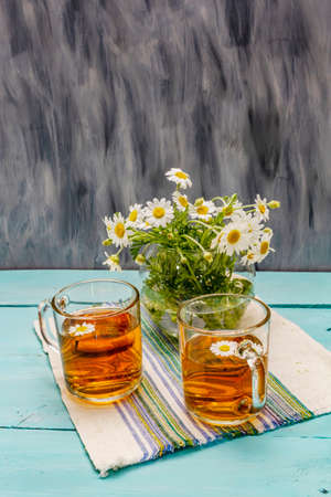 Chamomile tea. Fresh flowers, summer hot drink concept. Alternative medicine, lifestyle. Trendy turquoise wooden boards background, copy spaceの写真素材