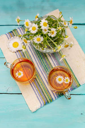Chamomile tea. Fresh flowers, summer hot drink concept. Alternative medicine, lifestyle. Trendy turquoise wooden boards background, top viewの写真素材