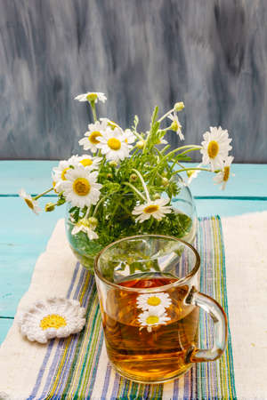 Chamomile tea. Fresh flowers, summer hot drink concept. Alternative medicine, lifestyle. Trendy turquoise wooden boards background, copy spaceの写真素材