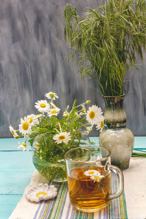 Chamomile tea. Fresh flowers, summer hot drink concept. Alternative medicine, lifestyle. Trendy turquoise wooden boards background, copy spaceの写真素材