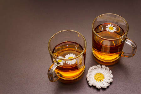 Chamomile tea. Fresh flowers, summer hot drink concept. Alternative medicine, lifestyle. Trendy black stone concrete background, top viewの写真素材