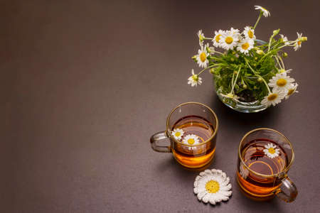 Chamomile tea. Fresh flowers, summer hot drink concept. Alternative medicine, lifestyle. Trendy black stone concrete background, top viewの写真素材