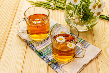 Chamomile tea. Fresh flowers, summer hot drink concept. Alternative medicine, lifestyle.Wooden boards background, copy spaceの写真素材