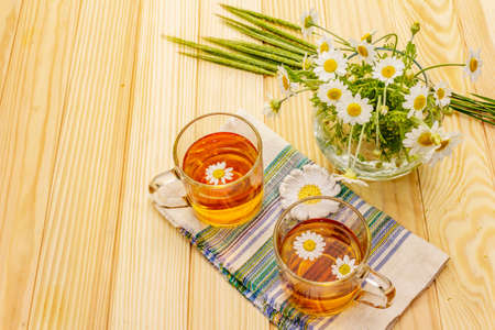 Chamomile tea. Fresh flowers, summer hot drink concept. Alternative medicine, lifestyle.Wooden boards background, copy spaceの写真素材