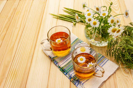Chamomile tea. Fresh flowers, summer hot drink concept. Alternative medicine, lifestyle.Wooden boards background, copy spaceの写真素材