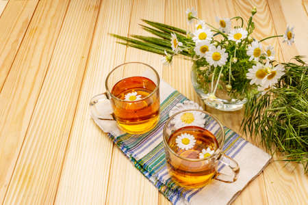 Chamomile tea. Fresh flowers, summer hot drink concept. Alternative medicine, lifestyle.Wooden boards background, copy spaceの写真素材