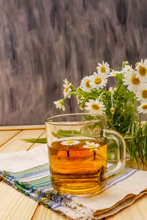 Chamomile tea. Fresh flowers, summer hot drink concept. Alternative medicine, lifestyle.Wooden boards background, copy spaceの写真素材