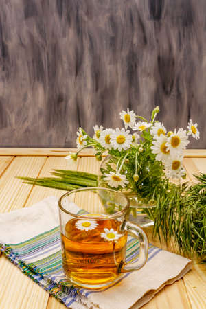 Chamomile tea. Fresh flowers, summer hot drink concept. Alternative medicine, lifestyle.Wooden boards background, copy spaceの写真素材