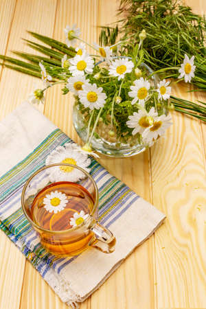 Chamomile tea. Fresh flowers, summer hot drink concept. Alternative medicine, lifestyle.Wooden boards background, copy spaceの写真素材