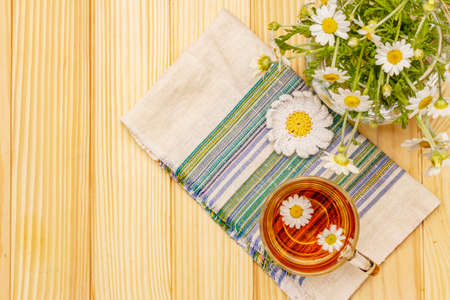 Chamomile tea. Fresh flowers, summer hot drink concept. Alternative medicine, lifestyle.Wooden boards background, top viewの写真素材