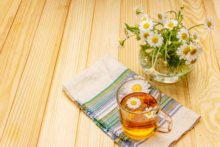 Chamomile tea. Fresh flowers, summer hot drink concept. Alternative medicine, lifestyle.Wooden boards background, copy spaceの写真素材