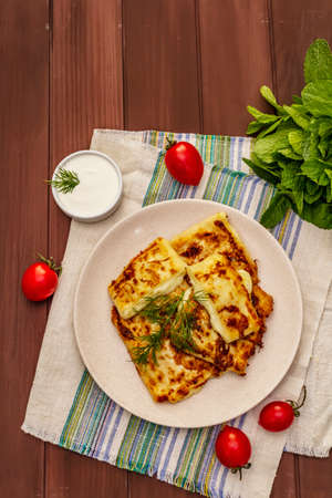 Hot appetizer - pita bread with cheese and herbs. Vegetarian healthy food. Wood table background, top viewの写真素材
