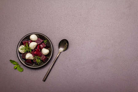 Culinary background. Cooking food concept. Healthy salad with baked beetroot, baby mozzarella, fresh greens. Trendy black stone concrete backdrop, top viewの写真素材