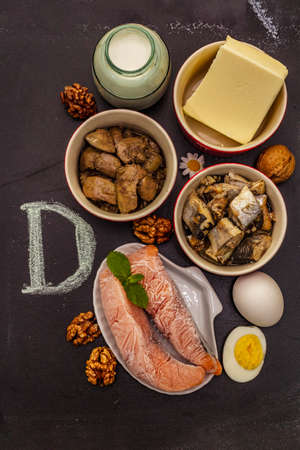 Foods containing vitamin D. Cheese, eggs, butter, nuts, milk, sardine. Black chalk board backgroundの写真素材