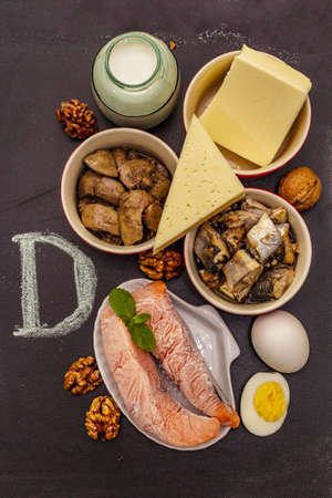 Foods containing vitamin D. Cheese, eggs, butter, nuts, milk, sardine. Black chalk board backgroundの写真素材