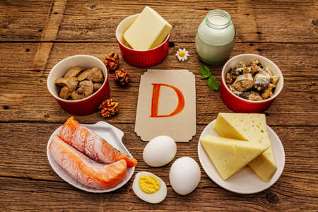 Foods containing vitamin D. Cheese, eggs, butter, nuts, milk, sardine, salmon, liver. Old wooden boards backgroundの写真素材