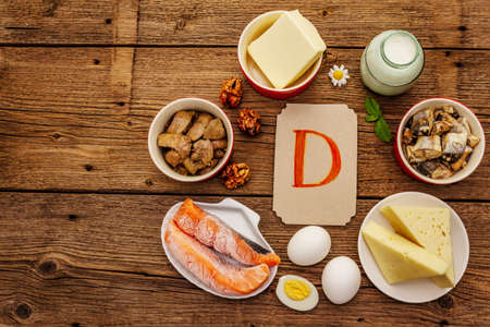 Foods containing vitamin D. Cheese, eggs, butter, nuts, milk, sardine, salmon, liver. Old wooden boards backgroundの写真素材