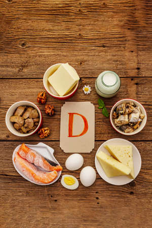 Foods containing vitamin D. Cheese, eggs, butter, nuts, milk, sardine, salmon, liver. Old wooden boards backgroundの写真素材