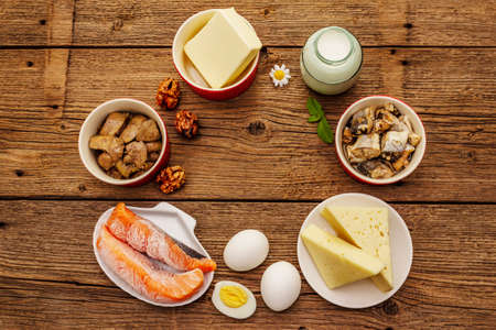 Foods containing vitamin D. Cheese, eggs, butter, nuts, milk, sardine, salmon, liver. Old wooden boards background, place for textの写真素材