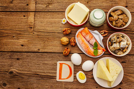 Foods containing vitamin D. Cheese, eggs, butter, nuts, milk, sardine, salmon, liver. Old wooden boards backgroundの写真素材