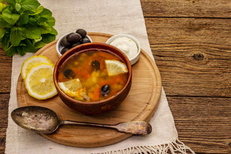 Hodgepodge, hot soup served in traditional ceramic bowl and pot. Classical Eastern Europe dish, old vintage wooden boards backgroundの写真素材