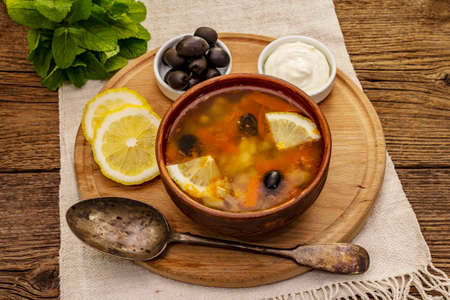 Hodgepodge, hot soup served in traditional ceramic bowl and pot. Classical Eastern Europe dish, old vintage wooden boards backgroundの写真素材
