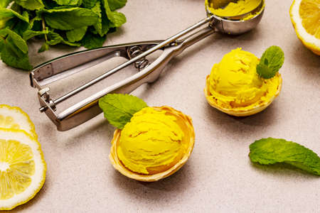 Lemon ice cream with mint. Refreshing summer dessert, ripe fruit, fragrant leaves. Stone concrete background, close upの写真素材
