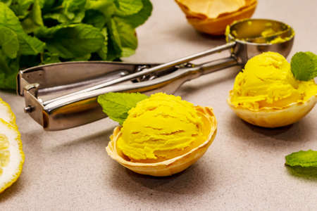 Lemon ice cream with mint. Refreshing summer dessert, ripe fruit, fragrant leaves. Stone concrete background, close upの写真素材