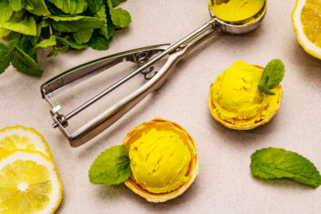 Lemon ice cream with mint. Refreshing summer dessert, ripe fruit, fragrant leaves. Stone concrete background, close upの写真素材