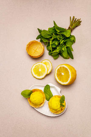Lemon ice cream with mint. Refreshing summer dessert, ripe fruit, fragrant leaves. Stone concrete background, top viewの写真素材