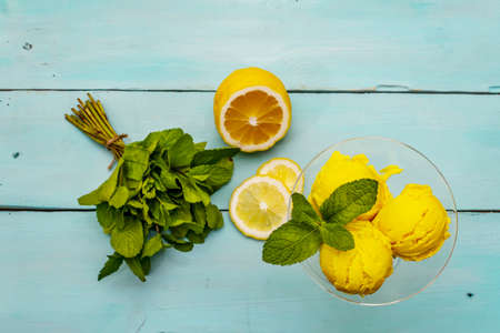 Lemon ice cream with mint. Refreshing summer dessert, ripe fruit, fragrant leaves. Trendy turquoise wooden background, top viewの写真素材