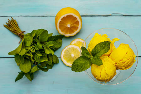 Lemon ice cream with mint. Refreshing summer dessert, ripe fruit, fragrant leaves. Trendy turquoise wooden background, top viewの写真素材