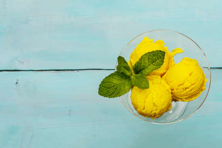 Lemon ice cream with mint. Refreshing summer dessert, ripe fruit, fragrant leaves. Trendy turquoise wooden background, top viewの写真素材