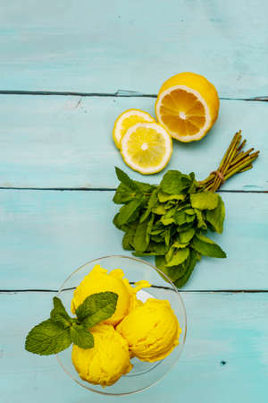 Lemon ice cream with mint. Refreshing summer dessert, ripe fruit, fragrant leaves. Trendy turquoise wooden background, top viewの写真素材