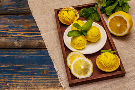 Lemon ice cream with mint. Refreshing summer dessert, ripe fruit, fragrant leaves. Wooden boards background, copy spaceの写真素材
