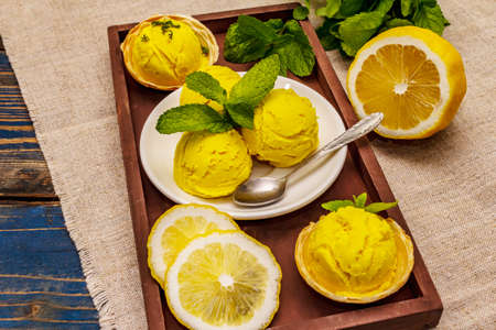 Lemon ice cream with mint. Refreshing summer dessert, ripe fruit, fragrant leaves. Wooden boards background, close upの写真素材